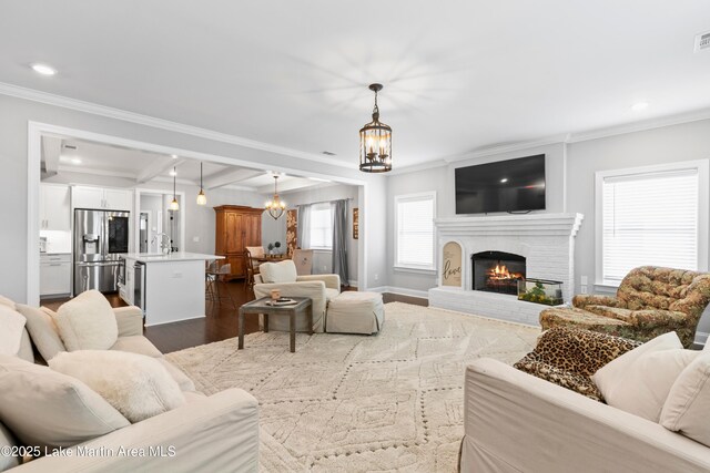 2409 Meadow Cove Rd, Auburn, AL 36832 - living area featuring ornamental molding, dark wood-style flooring, a chandelier, beamed ceiling, and a brick fireplace