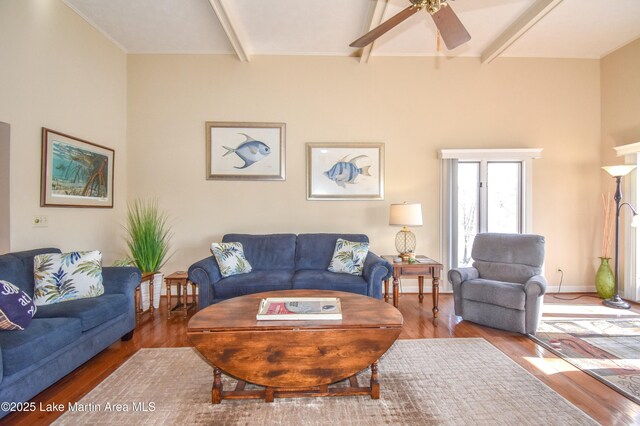 living room featuring hardwood / wood-style floors, beamed ceiling, and ceiling fan