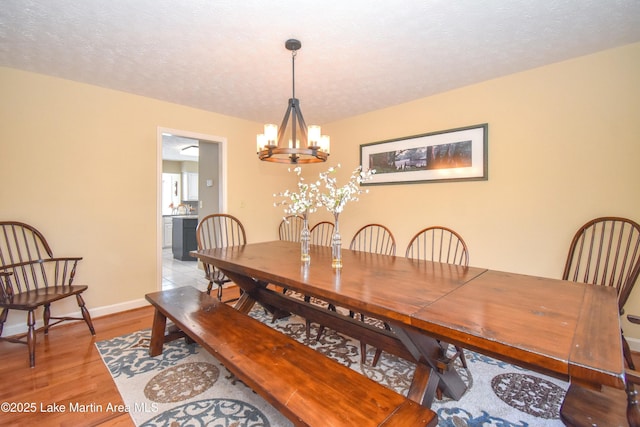 127 Ridge Crest Dr, Jacksons Gap, AL 36861 - dining area with a chandelier, light wood-style flooring, baseboards, and a textured ceiling