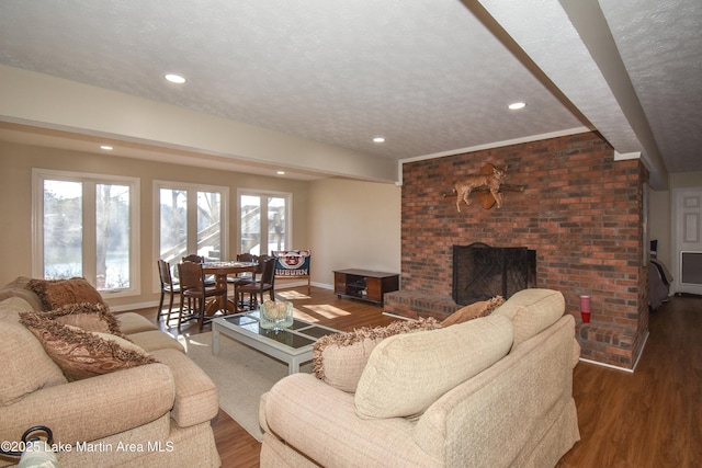 127 Ridge Crest Dr, Jacksons Gap, AL 36861 - living room with wood finished floors, baseboards, a brick fireplace, recessed lighting, and a textured ceiling