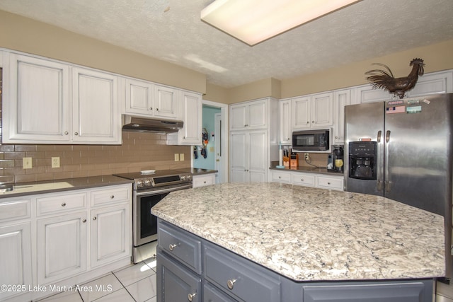 kitchen with stainless steel appliances, tasteful backsplash, a center island, and white cabinets