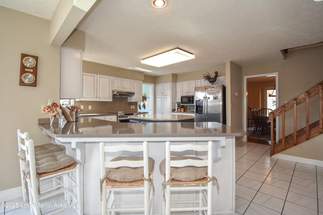 127 Ridge Crest Dr, Jacksons Gap, AL 36861 - kitchen featuring appliances with stainless steel finishes, under cabinet range hood, white cabinets, backsplash, and a peninsula