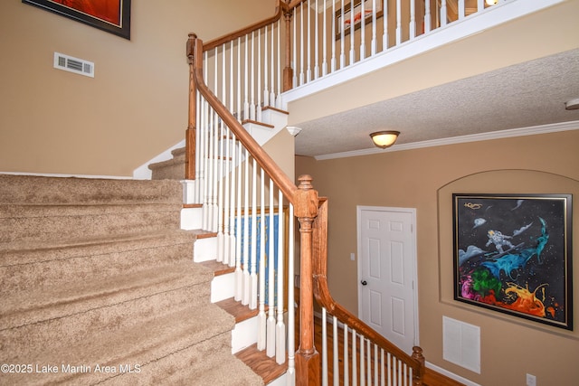 stairway with wood-type flooring, ornamental molding, and a textured ceiling