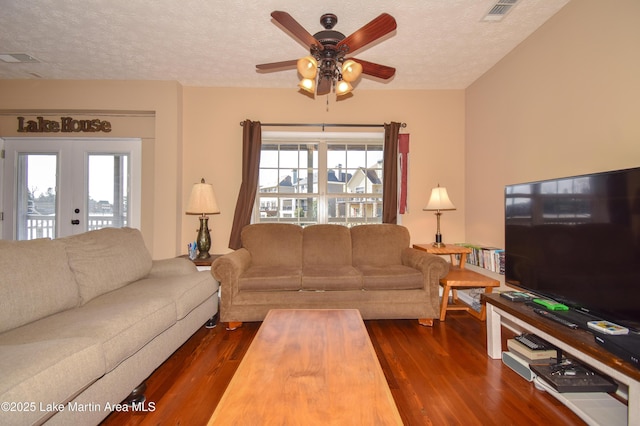 living room with a healthy amount of sunlight, a textured ceiling, dark hardwood / wood-style flooring, and french doors