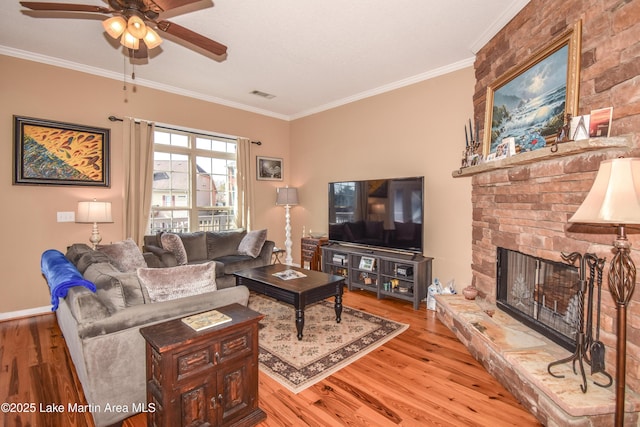 living room with crown molding, a stone fireplace, and light hardwood / wood-style flooring