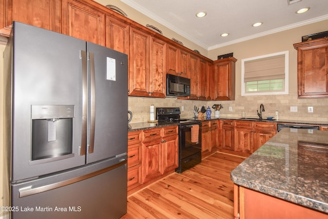 kitchen with dark stone counters, light hardwood / wood-style flooring, decorative backsplash, and black appliances