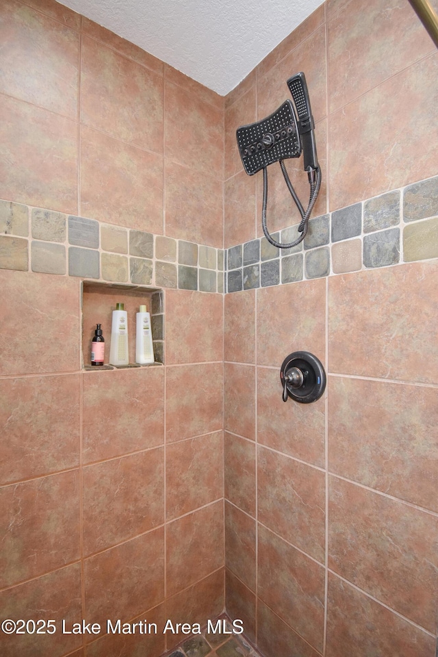 bathroom with a tile shower and a textured ceiling