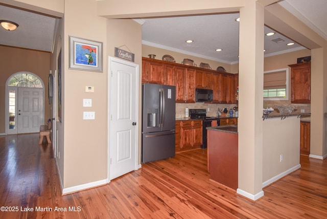 kitchen featuring tasteful backsplash, ornamental molding, black appliances, and light hardwood / wood-style floors