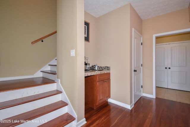 stairs featuring hardwood / wood-style floors, sink, and a textured ceiling