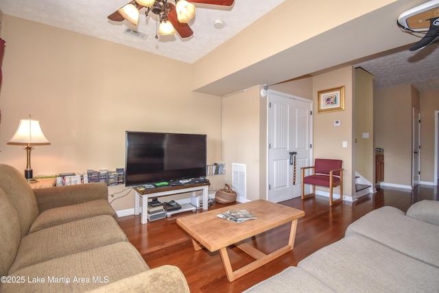 living room with a textured ceiling, dark hardwood / wood-style floors, and ceiling fan