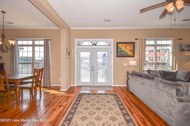 foyer featuring french doors, a healthy amount of sunlight, crown molding, and light wood-type flooring