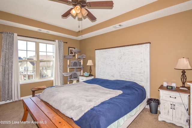 bedroom with ceiling fan, a tray ceiling, and carpet floors