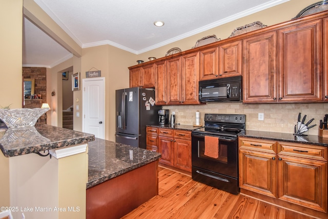 kitchen featuring tasteful backsplash, dark stone countertops, ornamental molding, black appliances, and light wood-type flooring