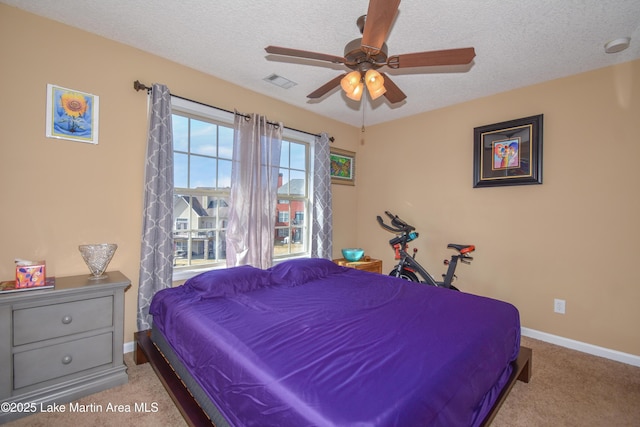 carpeted bedroom featuring ceiling fan and a textured ceiling