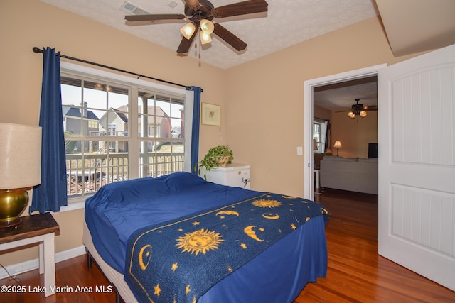 bedroom with multiple windows, ceiling fan, dark wood-type flooring, and a textured ceiling