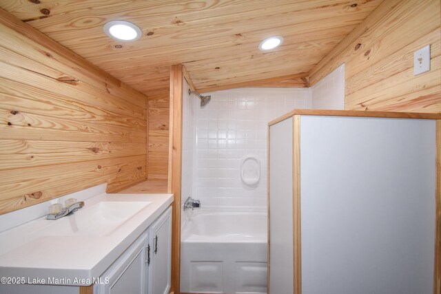 bathroom with wooden walls, vanity, wooden ceiling, and tiled shower / bath combo