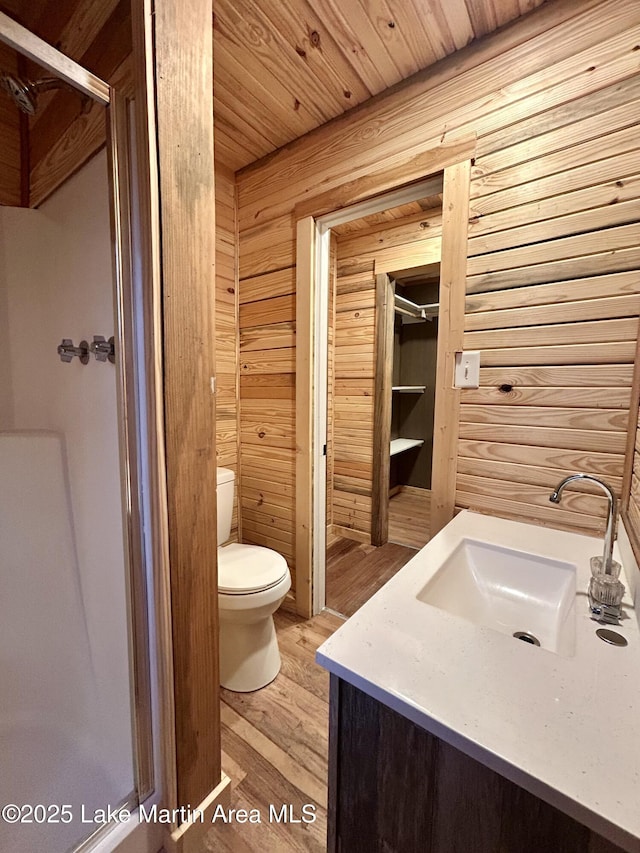 bathroom with hardwood / wood-style floors, toilet, wood walls, wooden ceiling, and vanity