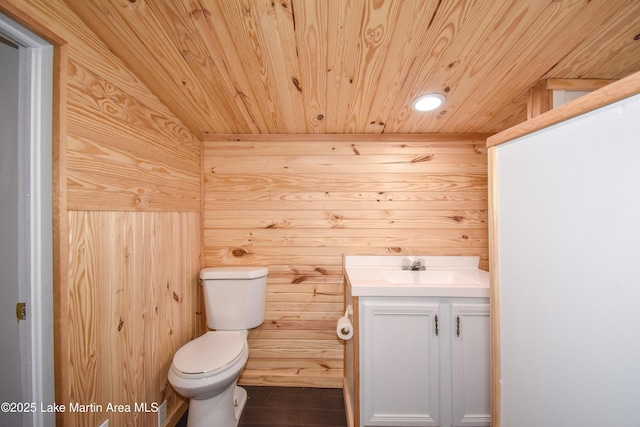 bathroom featuring wood walls, vanity, toilet, and wooden ceiling