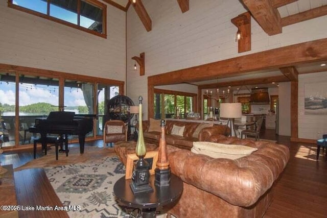 living room with a high ceiling, wood-type flooring, a healthy amount of sunlight, and beam ceiling