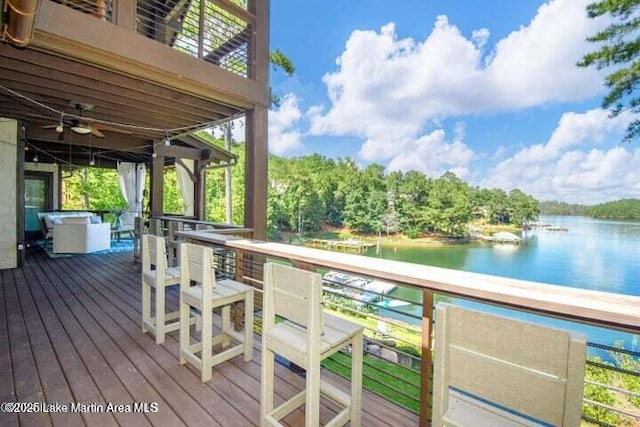 wooden deck with a water view and ceiling fan