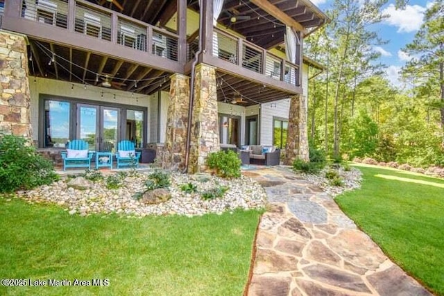 rear view of property featuring an outdoor hangout area, a patio area, a balcony, and a lawn