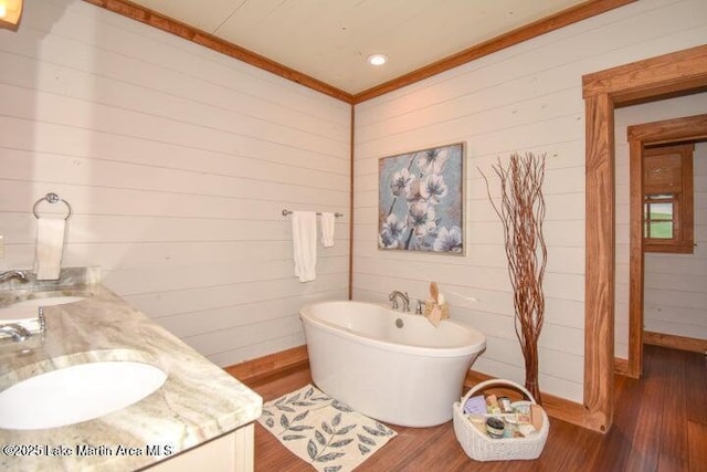 bathroom with ornamental molding, vanity, hardwood / wood-style floors, and a tub