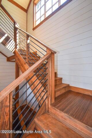 staircase featuring vaulted ceiling, hardwood / wood-style floors, and wood walls