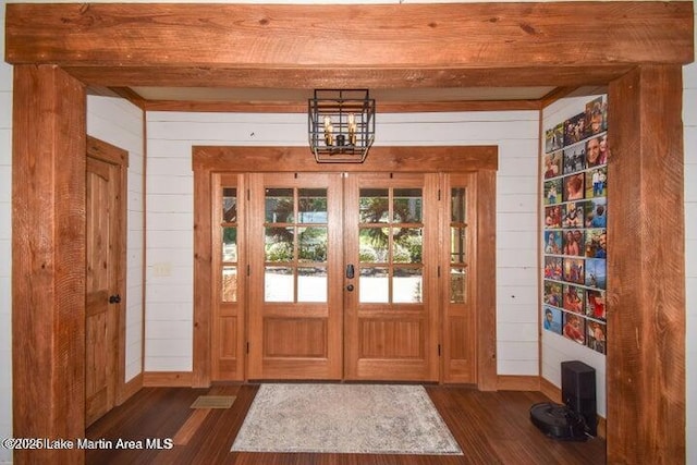 entryway featuring wooden walls, dark hardwood / wood-style floors, and beamed ceiling