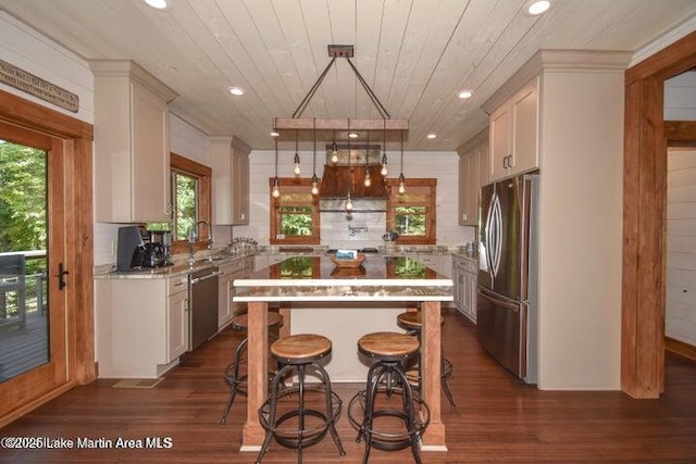 kitchen featuring appliances with stainless steel finishes, sink, hanging light fixtures, a center island, and wooden ceiling