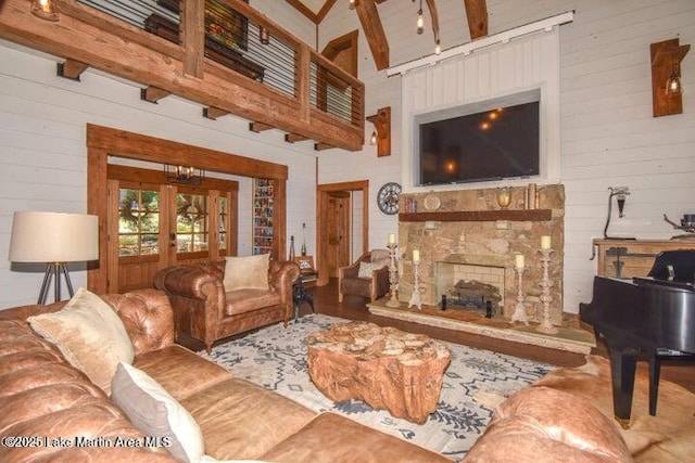 living room featuring a towering ceiling, a fireplace, french doors, and wooden walls