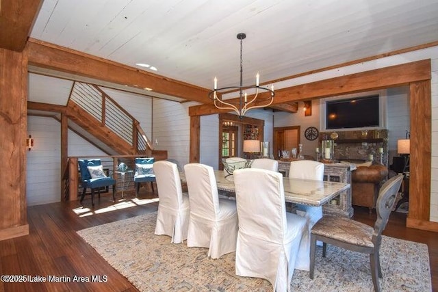 dining room featuring beamed ceiling, dark wood-type flooring, wooden walls, and a chandelier