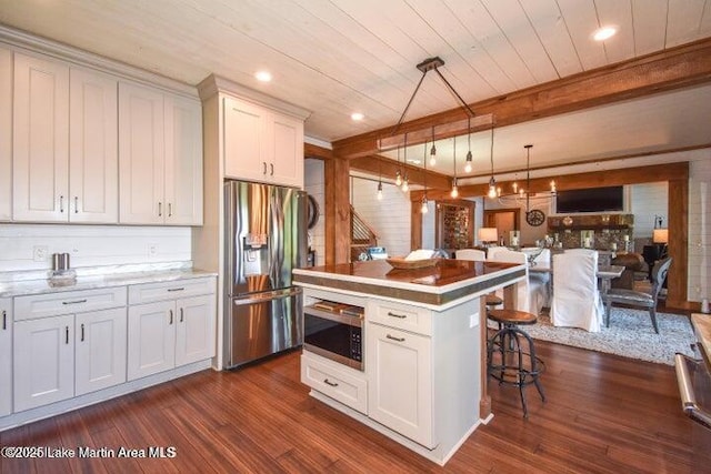 kitchen featuring white cabinetry, a center island, hanging light fixtures, appliances with stainless steel finishes, and dark hardwood / wood-style flooring