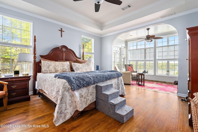 876 Ridge Rd, Dadeville, AL 36853 - bedroom with arched walkways, multiple windows, wood finished floors, a tray ceiling, and crown molding