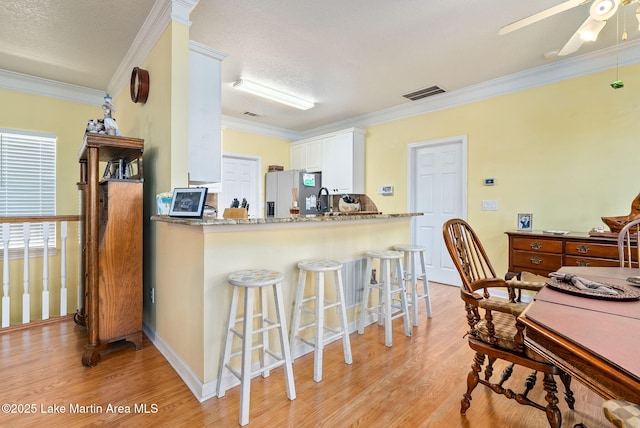 876 Ridge Rd, Dadeville, AL 36853 - kitchen featuring stainless steel fridge with ice dispenser, ornamental molding, light wood-style flooring, ceiling fan, and white cabinets