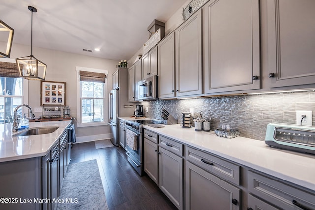 kitchen with pendant lighting, appliances with stainless steel finishes, and gray cabinetry