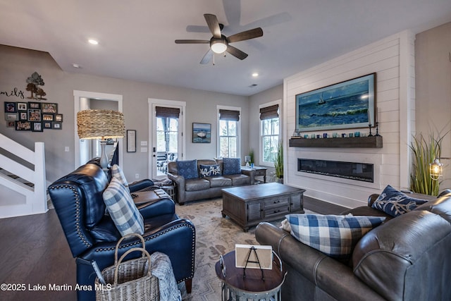 living room featuring a large fireplace, hardwood / wood-style floors, and ceiling fan