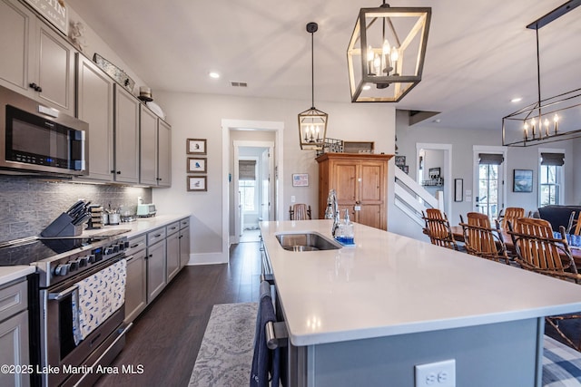 kitchen featuring a kitchen island with sink, sink, gray cabinets, and appliances with stainless steel finishes