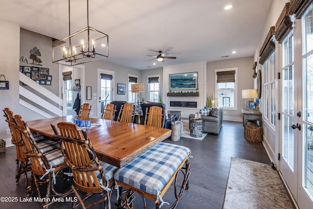 dining area featuring dark wood-type flooring, ceiling fan, a fireplace, and french doors