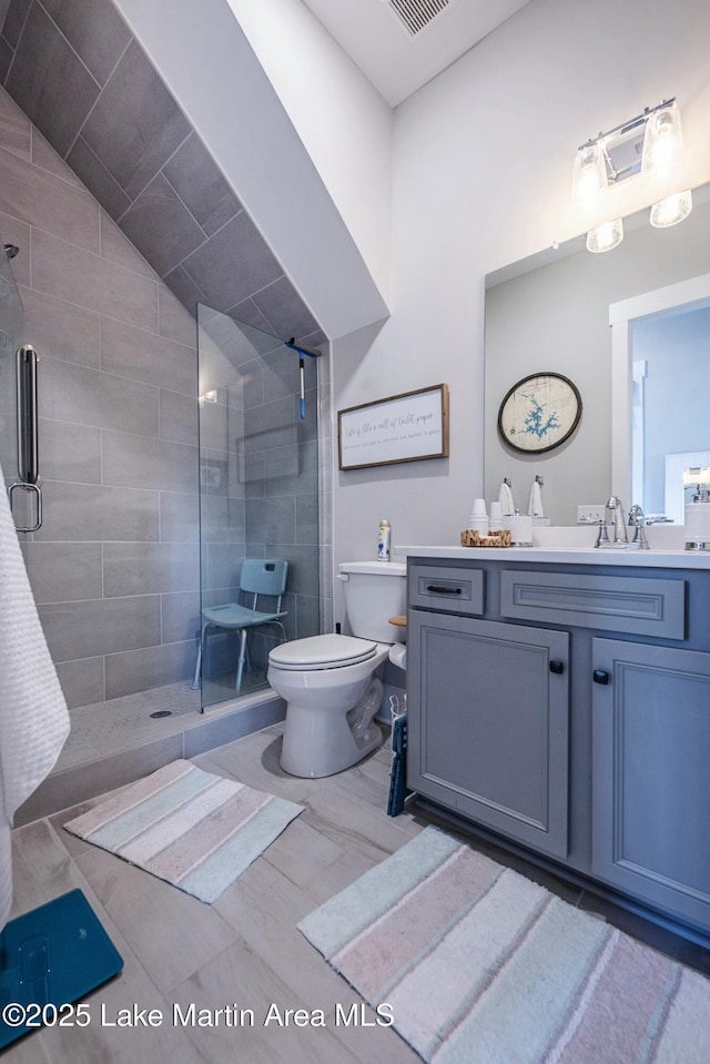 bathroom with vanity, a shower with shower door, lofted ceiling, and toilet