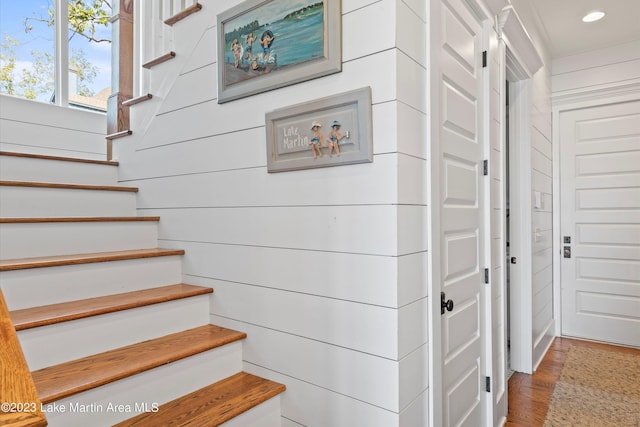 stairs featuring wood-type flooring and wooden walls