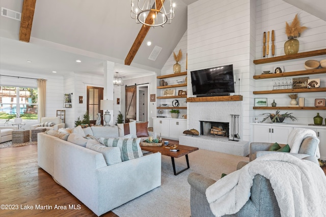 living room with a fireplace, beam ceiling, a barn door, and wood walls