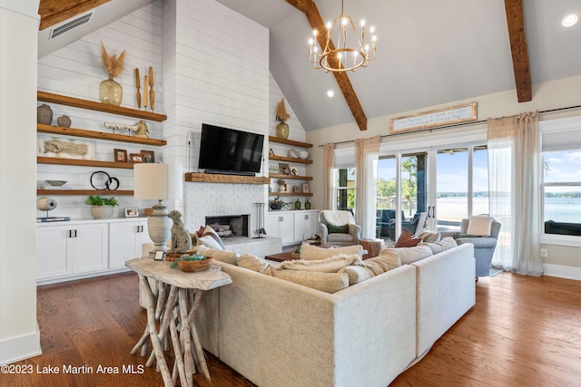 living room with beam ceiling, high vaulted ceiling, a chandelier, wood-type flooring, and a fireplace