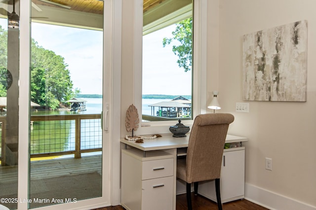 office area with a water view, dark wood-type flooring, and built in desk