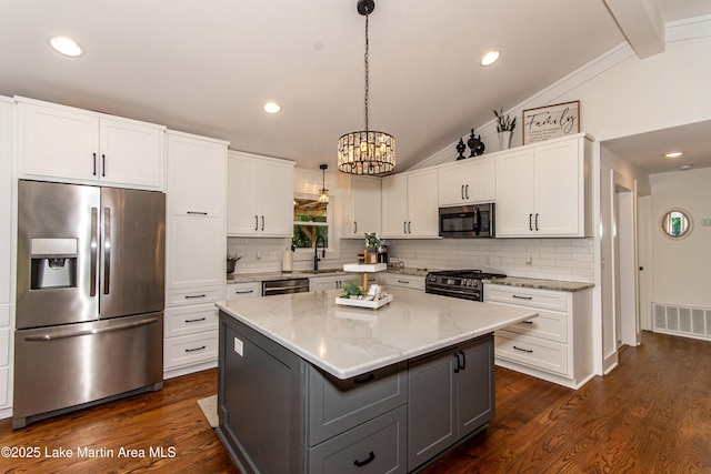 kitchen with pendant lighting, appliances with stainless steel finishes, white cabinetry, vaulted ceiling with beams, and a center island