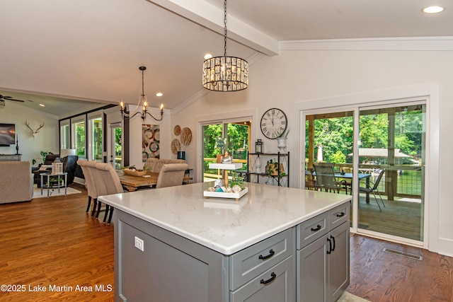 kitchen with gray cabinets, a kitchen island, decorative light fixtures, lofted ceiling with beams, and light stone counters