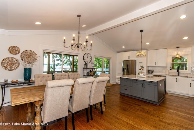 dining room with lofted ceiling with beams, sink, an inviting chandelier, and dark hardwood / wood-style flooring