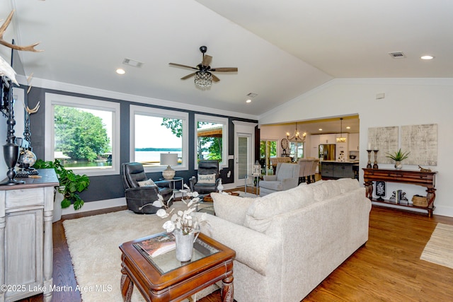 living room with ornamental molding, lofted ceiling, ceiling fan with notable chandelier, and light wood-type flooring