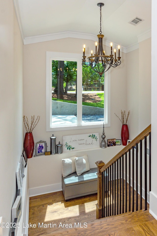 sitting room with an inviting chandelier, hardwood / wood-style floors, and ornamental molding