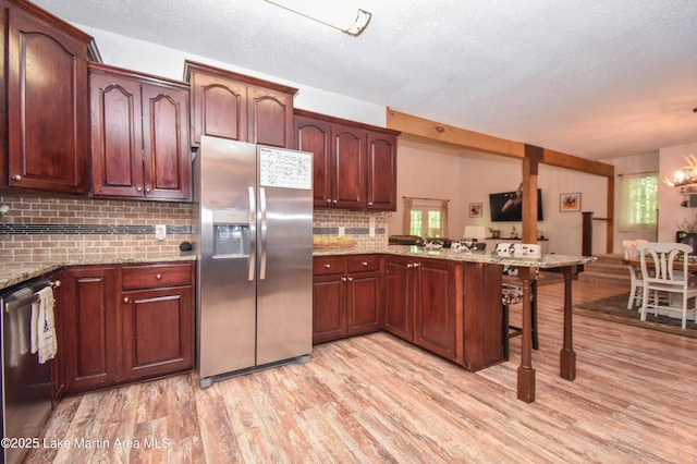 93 Restful Cv, Dadeville, AL 36853 - kitchen featuring appliances with stainless steel finishes, a peninsula, a breakfast bar, light wood-type flooring, and a textured ceiling