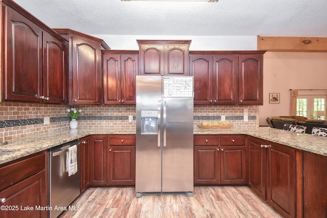 93 Restful Cv, Dadeville, AL 36853 - kitchen with stainless steel appliances, light wood-type flooring, light stone countertops, tasteful backsplash, and a textured ceiling